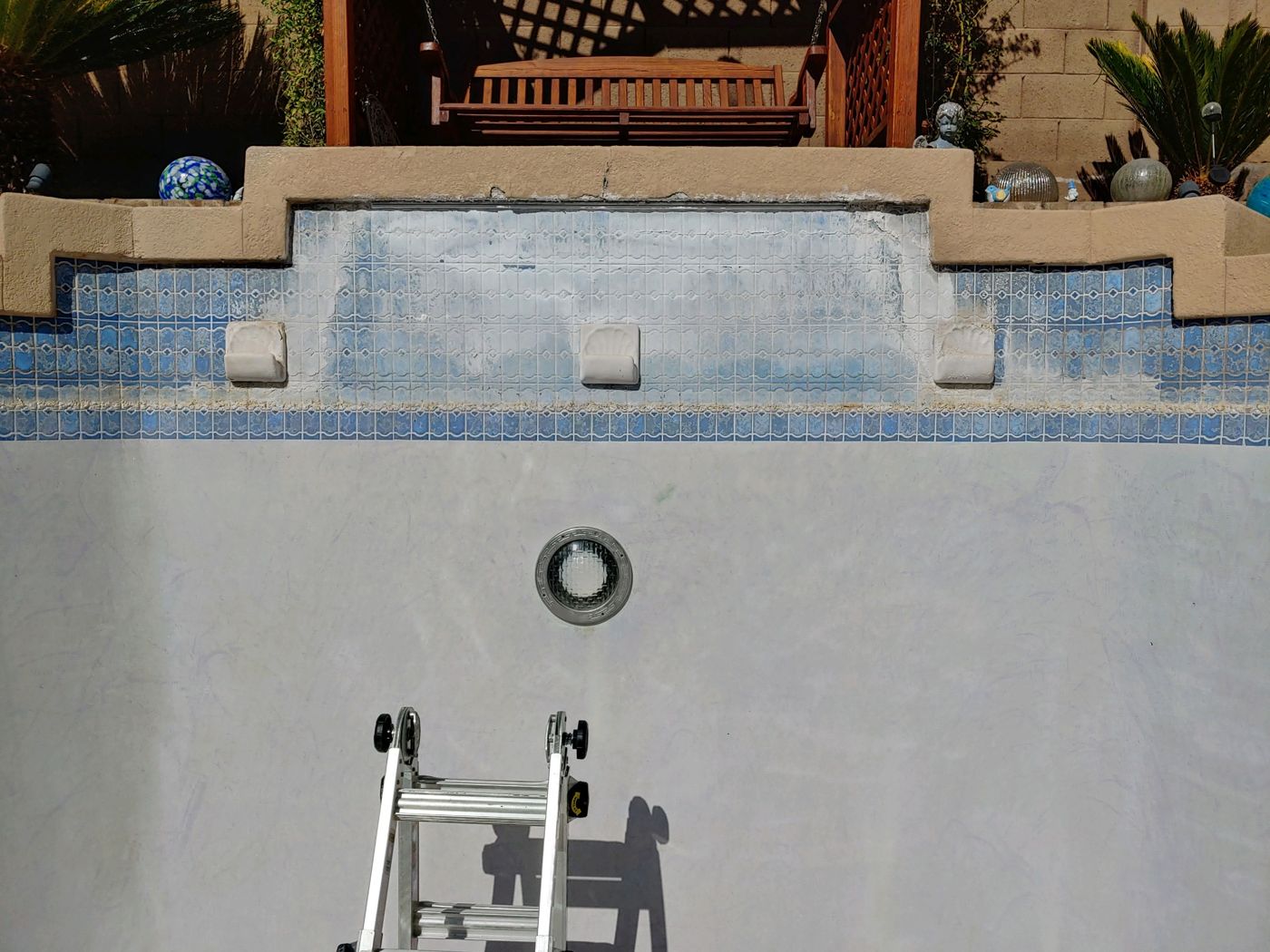 Drained Arizona pool showing heavy white calcium scale on the waterline tile before cleaning